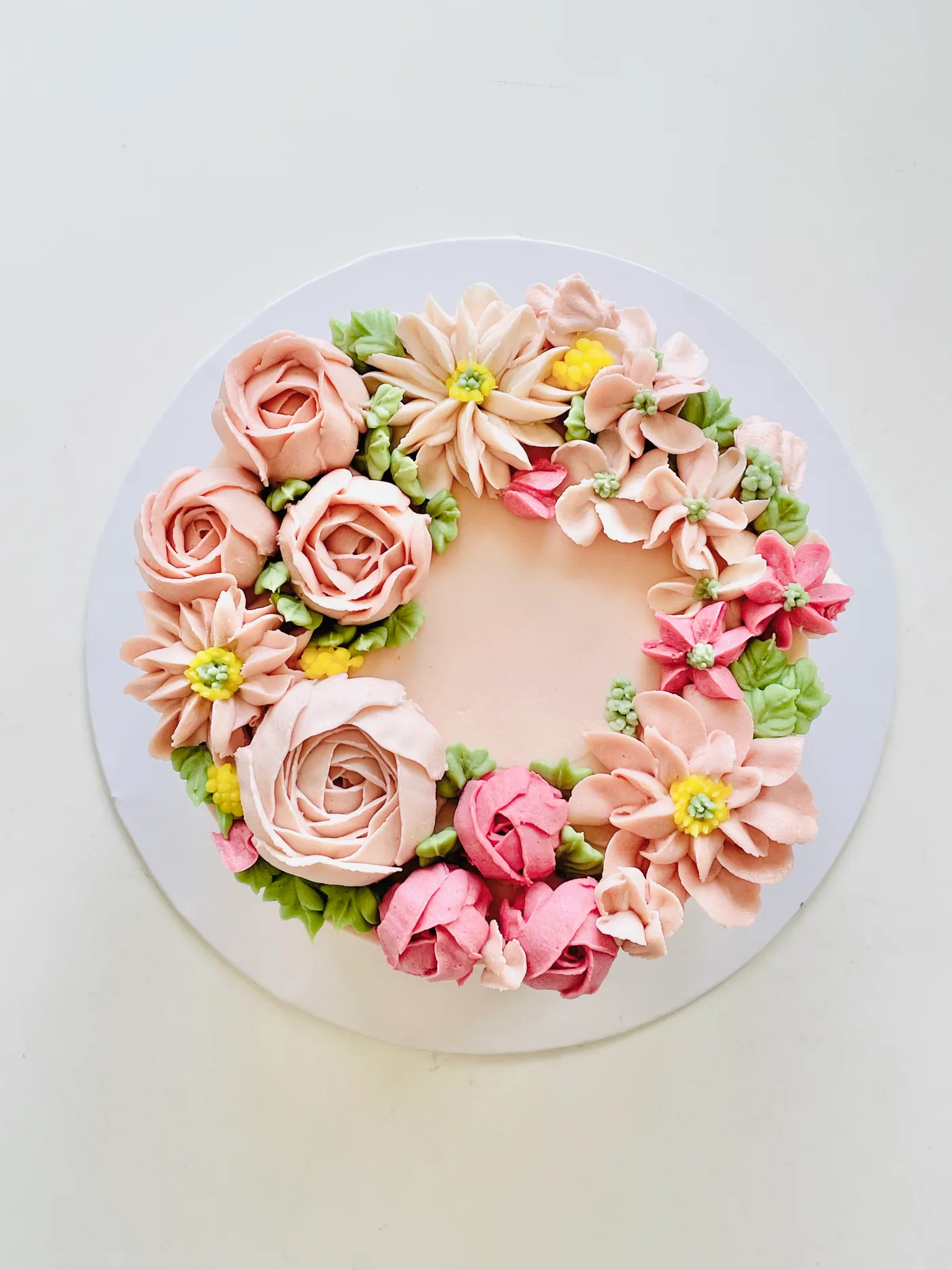 A buttercream bloom wreath cake in blush and rose