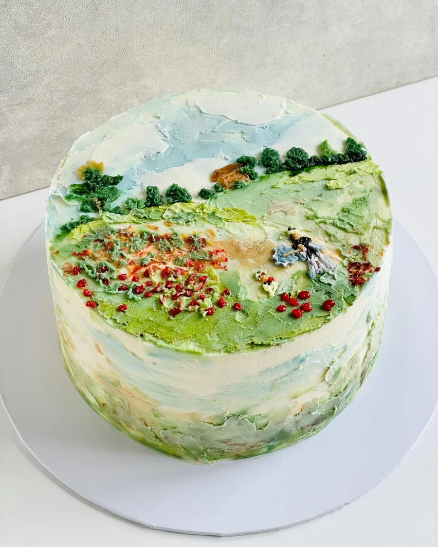 A hand-painted meadow landscape cake in buttercream, poppies and a figure in a field