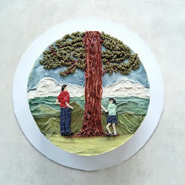 A hand-painted cake of two people under a tree