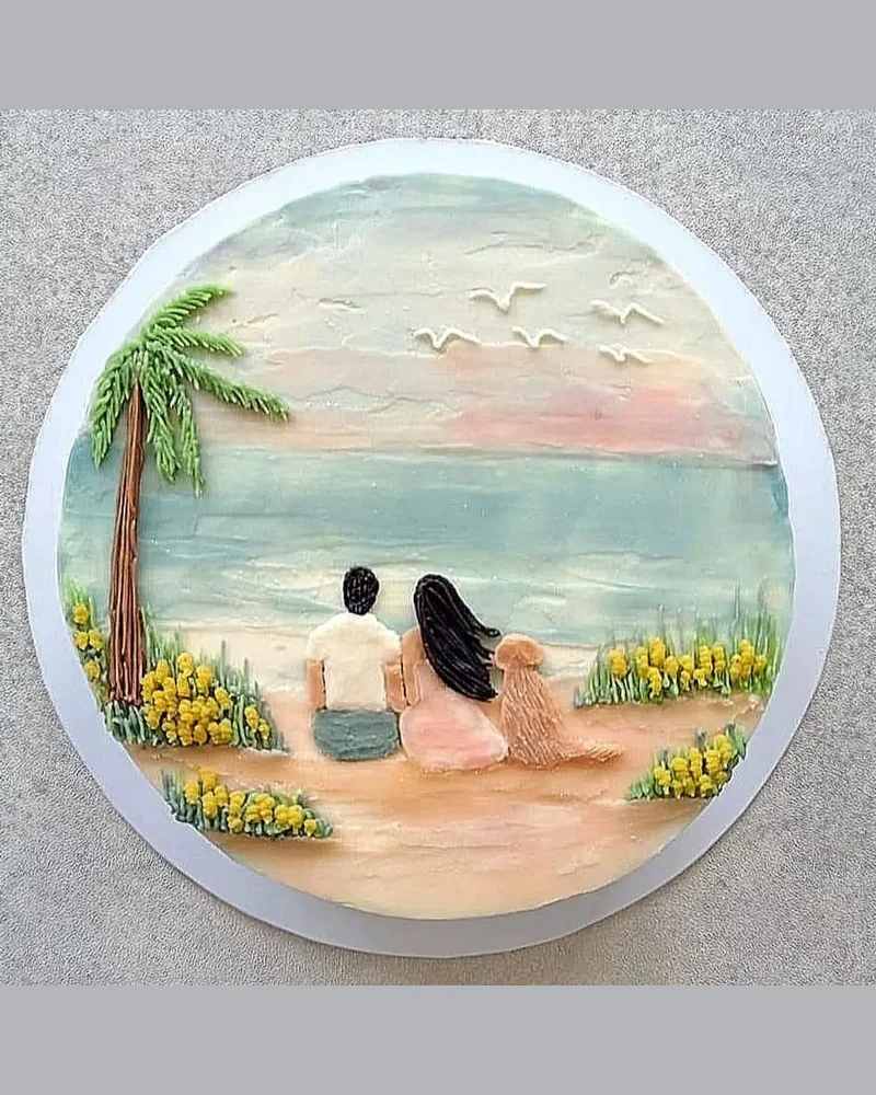 A hand-painted cake of a couple watching the sunset