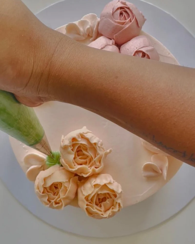 Piping buttercream roses by hand