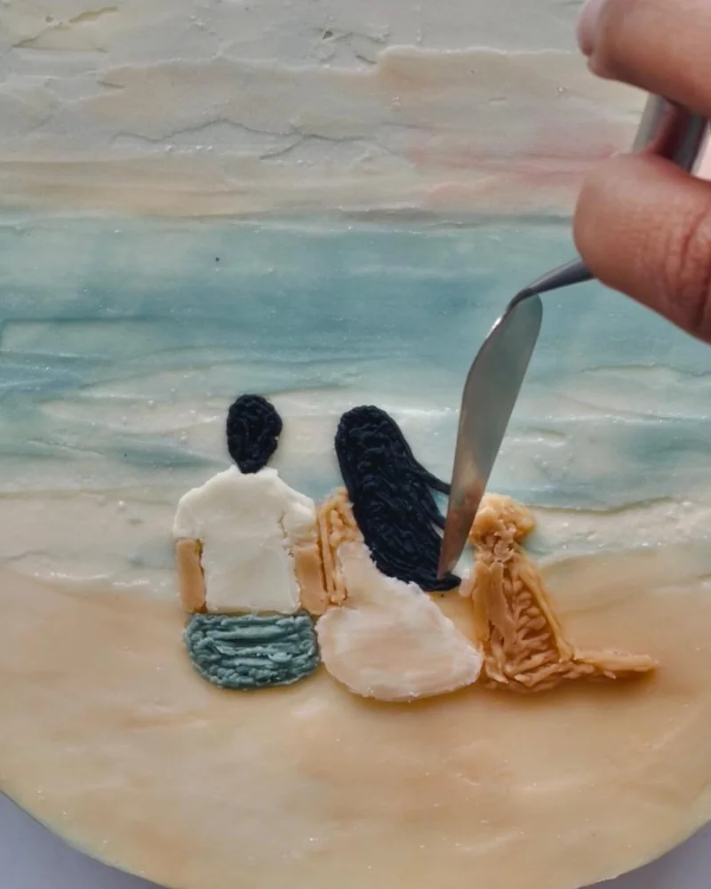 Hand-painting a scene onto a cake in buttercream