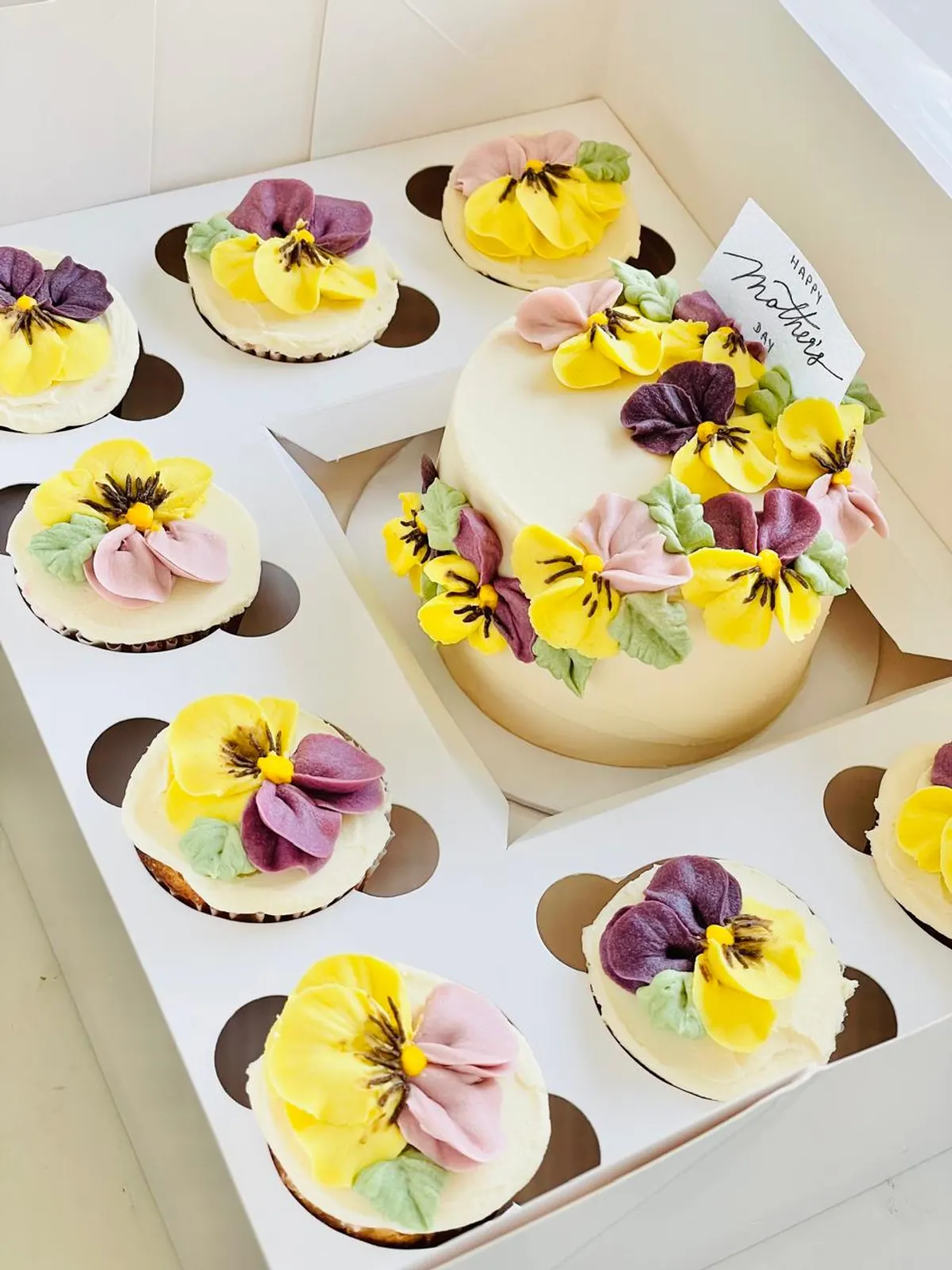 A Mother's Day cake with pansies and matching cupcakes
